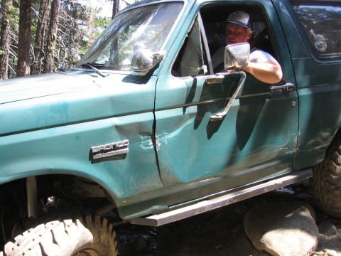 1989 Ford Bronco - Driver's side view of a green 1989 Ford Bronco showing significant damage to the door.