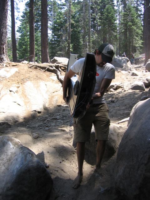 1989 Ford Bronco - A person carries a car door through a , outdoor environment with trees and rocks.