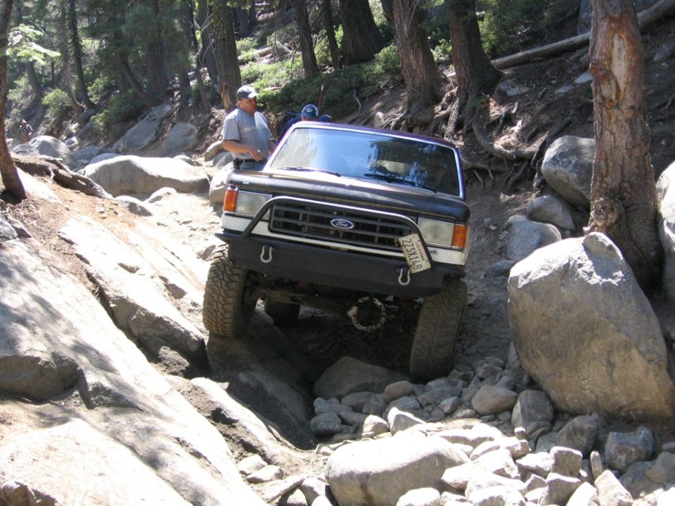 Black Ford Bronco navigating a rocky, wooded trail