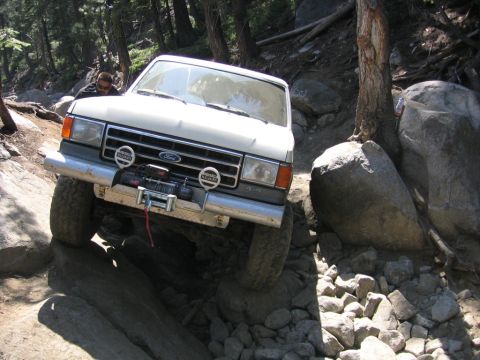 1989 Ford Bronco - This 1989 Ford Bronco is tackling a challenging rocky trail in a wooded area.