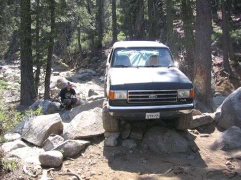 1989 Ford Bronco - A black 1989 Ford Bronco is shown navigating a challenging, rocky off-road trail.