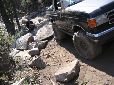 1989 Ford Bronco - Ford Bronco tackling a challenging off-road trail with significant rock obstacles.