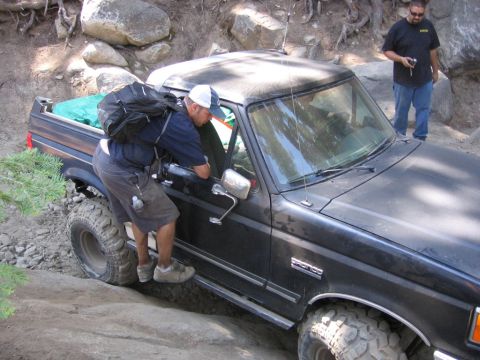 1989 Ford Bronco - Man climbs into a 1989 Ford Bronco navigating a rocky trail.