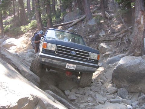 1989 Ford Bronco - This black Ford Bronco is shown tackling a challenging rocky terrain on an off-road trail.