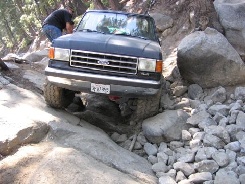 1989 Ford Bronco - Ford Bronco tackling a challenging off-road course with large rocks and steep inclines.