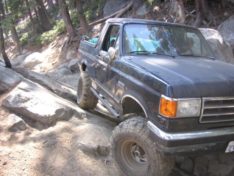 1989 Ford Bronco - This black Ford Bronco is shown tackling a challenging, rocky off-road path.