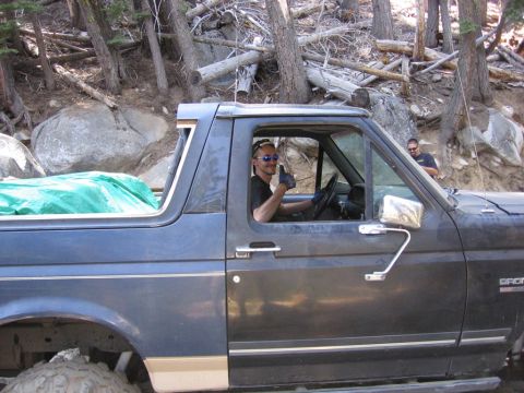 1989 Ford Bronco - A man in sunglasses gives a thumbs up from the driver's seat of a dark blue Ford Bronco.