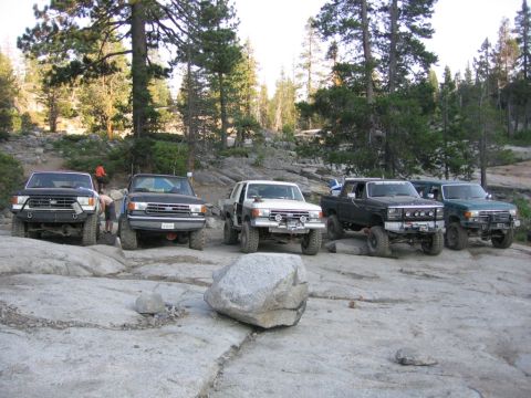 1989 Ford Bronco - A group of five 1989 Ford Broncos are parked on a rocky surface in a wooded area.