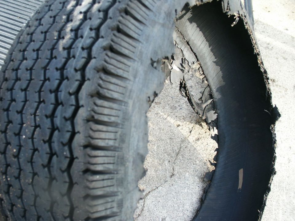 Tire with severe sidewall damage, showing exposed internal structure
