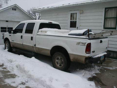 2000 Ford F-250 - A white 2000 Ford F-250 truck is parked in the snow with a ladder in the bed.