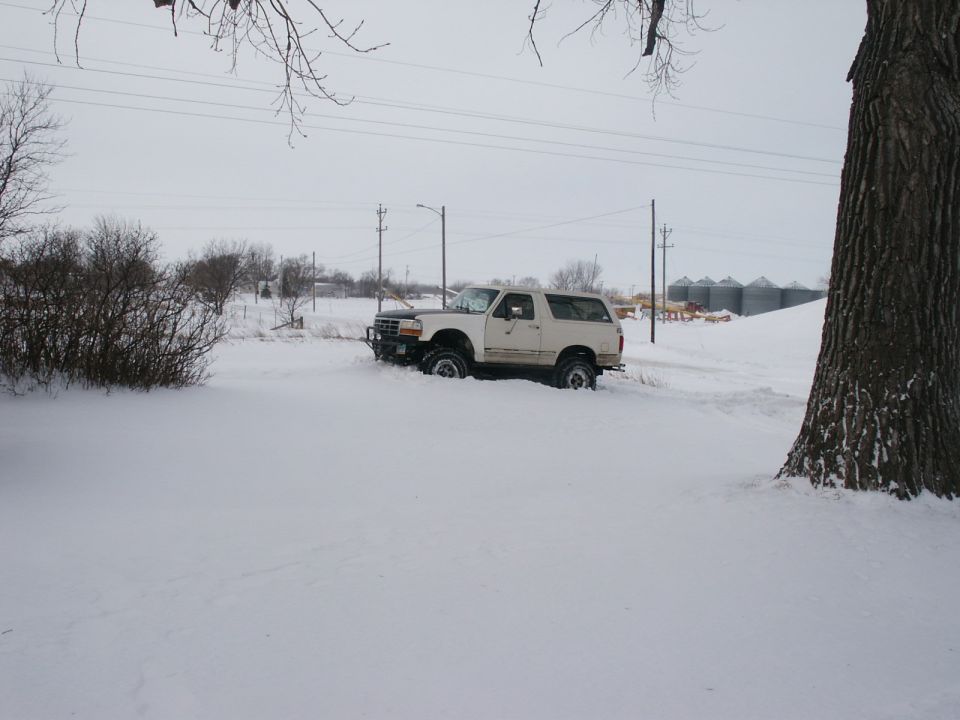 White Ford Bronco stuck in deep snow, front end partially buried