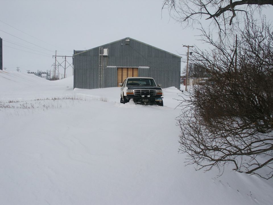 White and black Ford F-Series truck in snow, front view