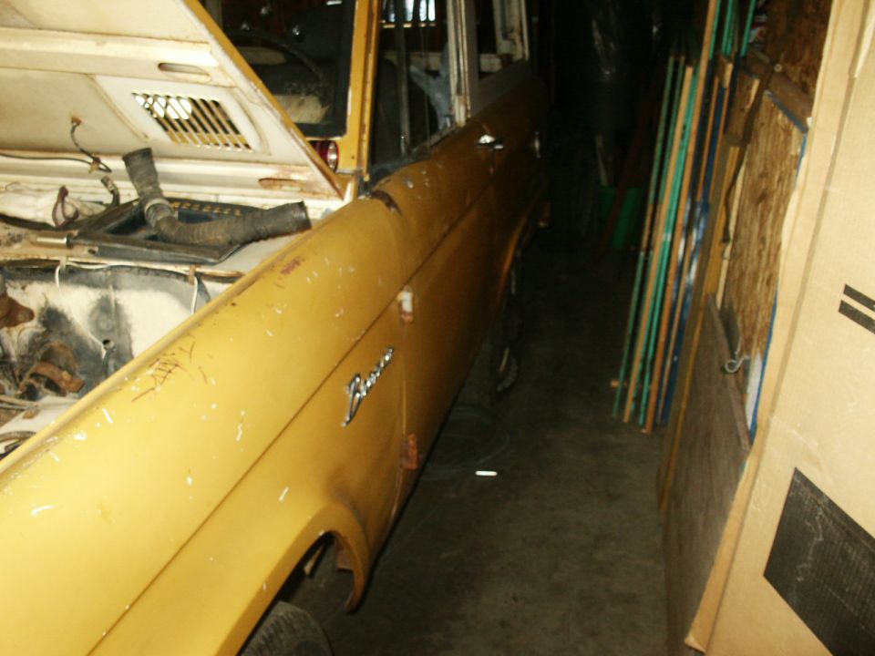 Yellow Ford Bronco with hood open, parked indoors next to stored items