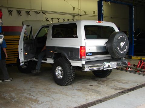 1995 Ford Bronco - This lifted Ford Bronco is parked inside a garage with its doors open, showing off its large tires.