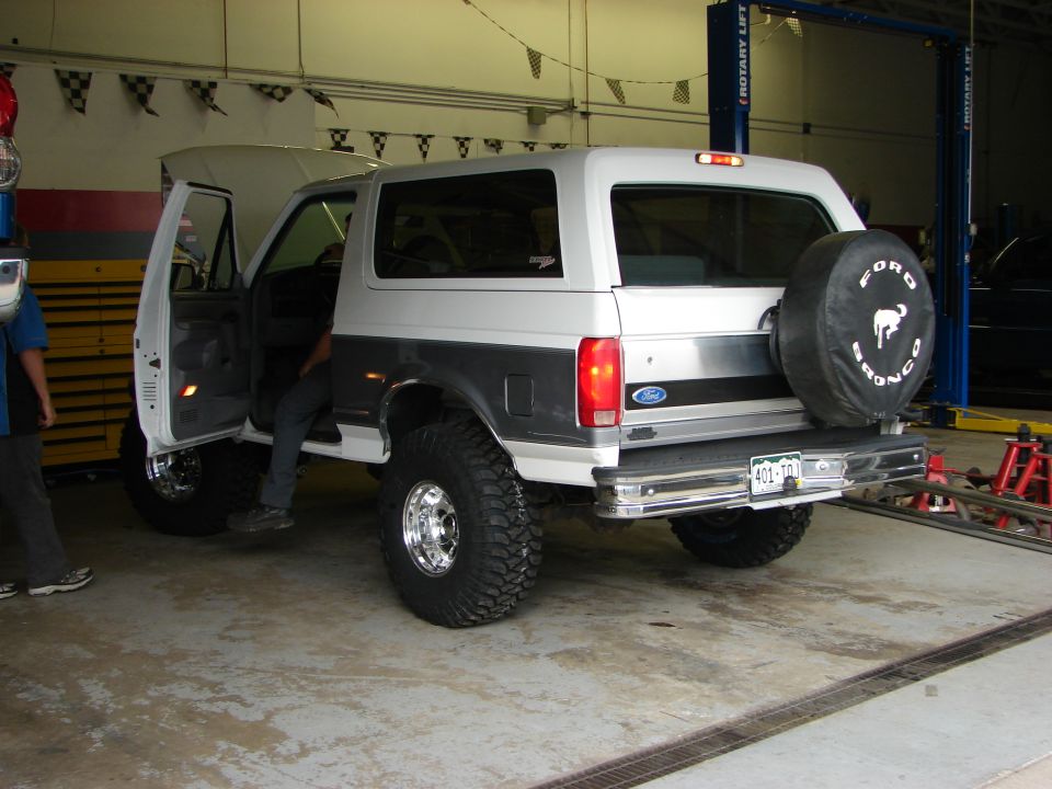 Lifted Ford Bronco with spare tire on back, doors open, in a garage