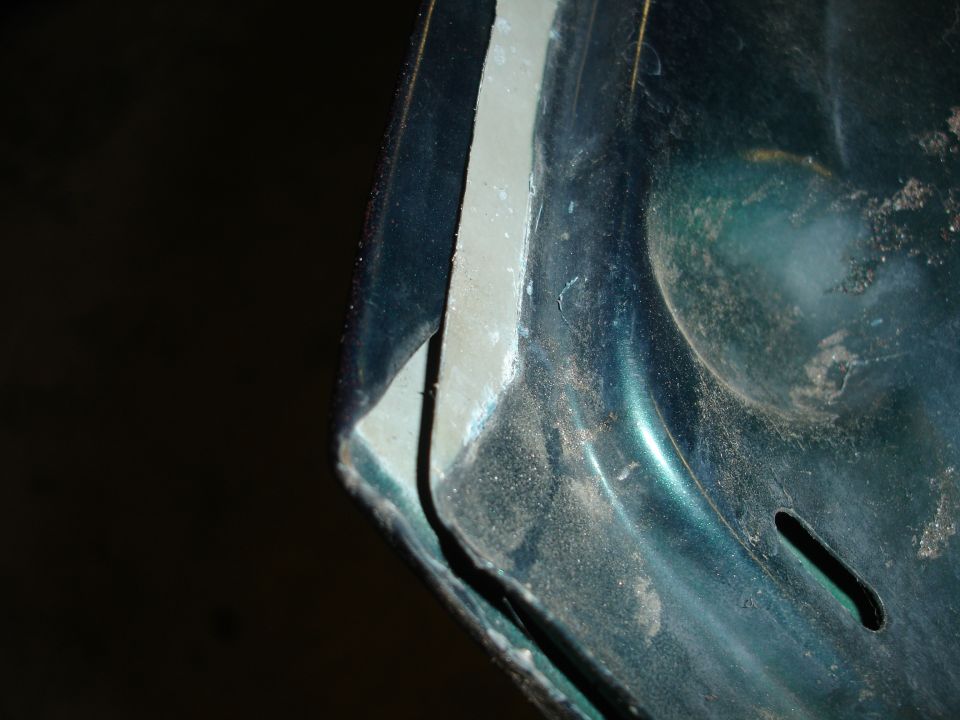 Close-up of a cut hood edge with green paint and dust