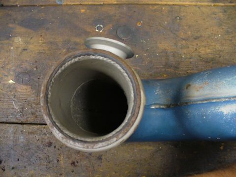1978 Ford Bronco - Exhaust pipe section with a silver flange shown on a workbench.