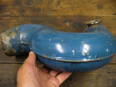 1978 Ford Bronco - A blue exhaust pipe part is held by a hand against a wooden background.