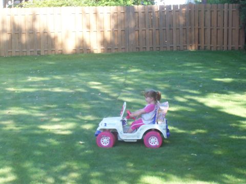 2000 Ford Crown Victoria - A young girl enjoys a ride in her toy jeep on a sunny day.