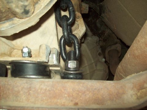 1985 Ford Bronco - Close-up view of the vehicle's undercarriage, showing mechanical components and a chain attachment.