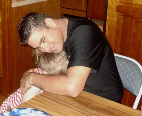 2000 Ford Crown Victoria - A man embraces a young child while seated at a table.