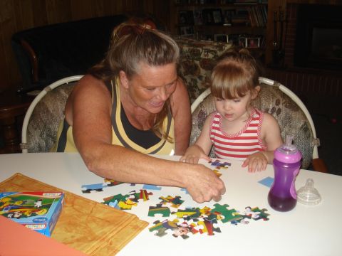 2000 Ford Crown Victoria - A woman and a young child are focused on completing a jigsaw puzzle together at a table.