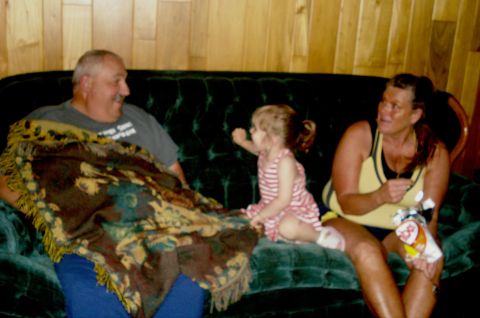 2000 Ford Crown Victoria - A family relaxes on a couch in a room with wood paneled walls.