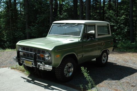 1973 Ford Bronco - This 1973 Ford Bronco is seen in a three-quarter front view, parked on a gravel surface with trees in the background.