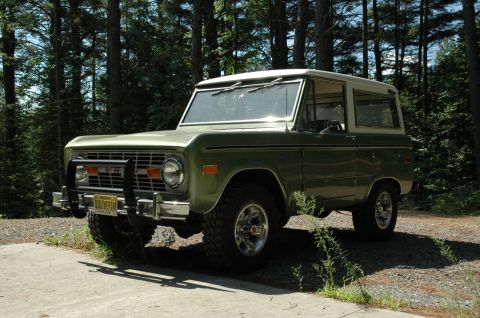 1973 Ford Bronco - 1973 Ford Bronco in a wooded area. The vehicle has a white hardtop and a chrome grille guard.