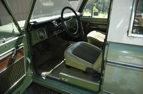 1973 Ford Bronco - The interior of a green 1973 Ford Bronco, plaid seat inserts and wood-grain trim on the door panels.