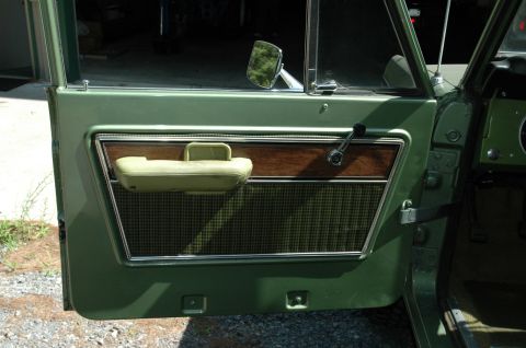 1973 Ford Bronco - Interior view of a vintage vehicle's green door panel, showing its textured fabric and wood accents.