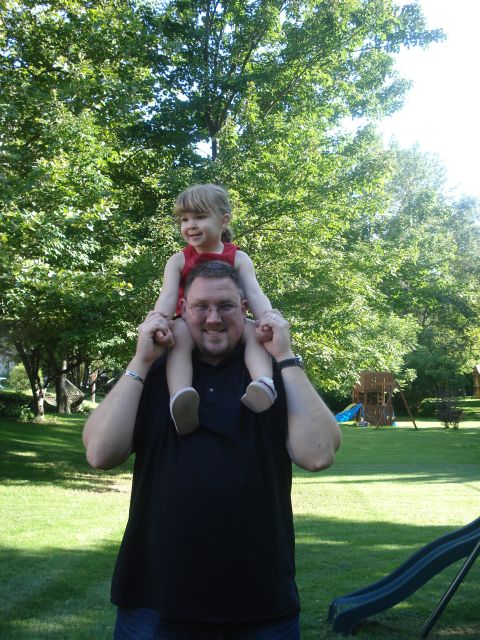 2000 Ford Crown Victoria - A father carries his daughter on his shoulders in a grassy backyard on a sunny day.