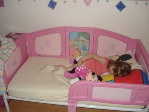 2000 Ford Crown Victoria - A young child rests in a pink toddler bed adorned with Disney princess imagery.