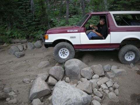 1991 Ford Bronco - 1991 Ford Bronco tackling a challenging off-road trail with large rocks.
