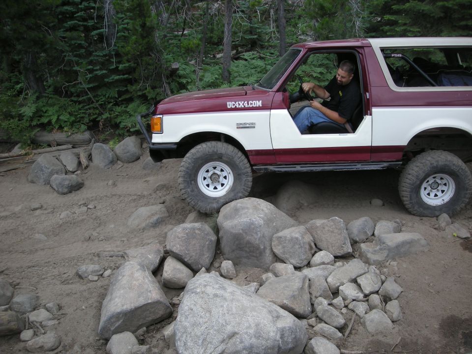 1991 Ford Bronco navigating rocky terrain, driver visible