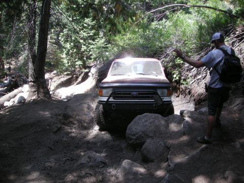 1991 Ford Bronco - This 1991 Ford Bronco is shown tackling a challenging off-road path with large rocks and dirt.