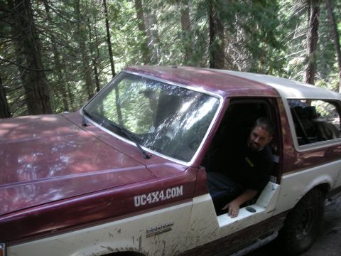 1991 Ford Bronco - A man sits in the open door of a maroon and white Ford Bronco, which has 'UC4X4.COM' written on its side.
