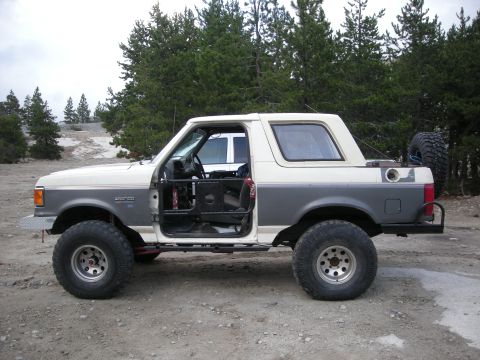 1991 Ford Bronco - This modified Ford Bronco features a two-tone paint scheme and lifted suspension, suggesting off-road use.