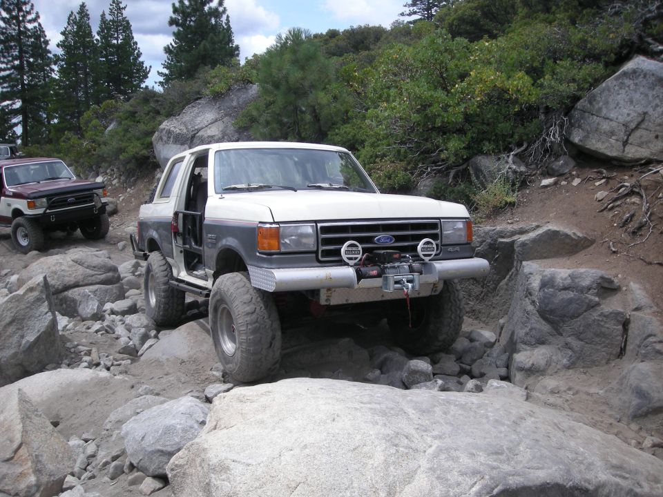 White and grey 1991 Ford Bronco navigating rocky terrain, front view