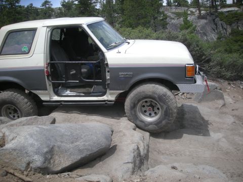 1991 Ford Bronco - This modified Ford Bronco navigates a rocky trail, its doors removed for off-road access.