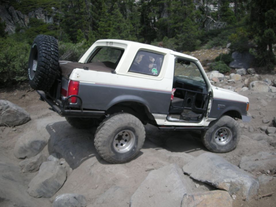 White and gray 1991 Ford Bronco off-roading with doors removed