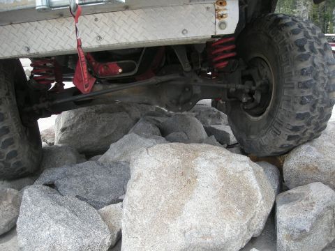 1991 Ford Bronco - Close-up of an off-road vehicle's suspension and tire navigating a rocky terrain.
