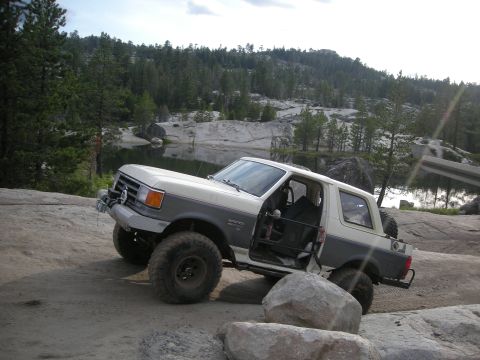 1991 Ford Bronco - This 1991 Ford Bronco is shown off-roading on a rocky trail with a lake in the background.