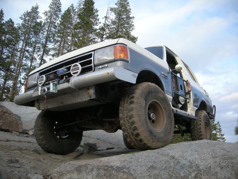 1991 Ford Bronco - Modified 1991 Ford Bronco navigating a rocky trail with large tires and a winch.