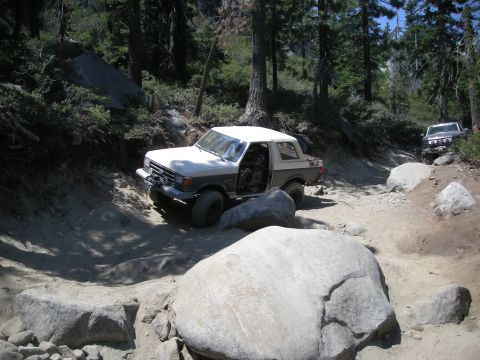 1991 Ford Bronco - A 1991 Ford Bronco tackles a challenging off-road course with a second vehicle following behind.