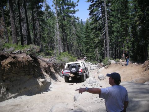 1991 Ford Bronco - A 1991 Ford Bronco navigates a challenging off-road trail in a wooded area.