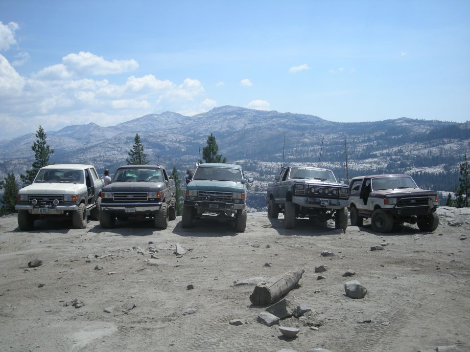 1991 Ford Bronco and four other trucks parked on a rocky mountain overlook