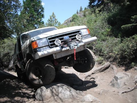 1991 Ford Bronco - Ford Bronco navigating a difficult off-road obstacle course with large rocks.