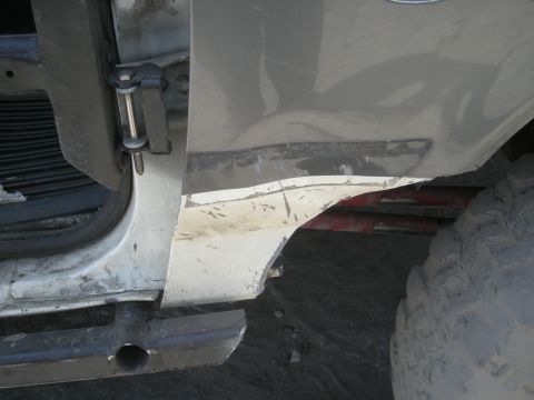 1991 Ford Bronco - Close-up view of a damaged vehicle body panel and a tire.