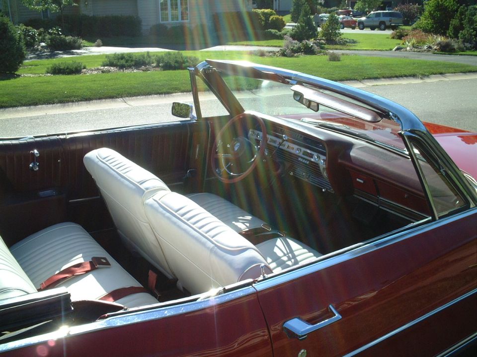 Interior of vintage red convertible with white seats parked curbside